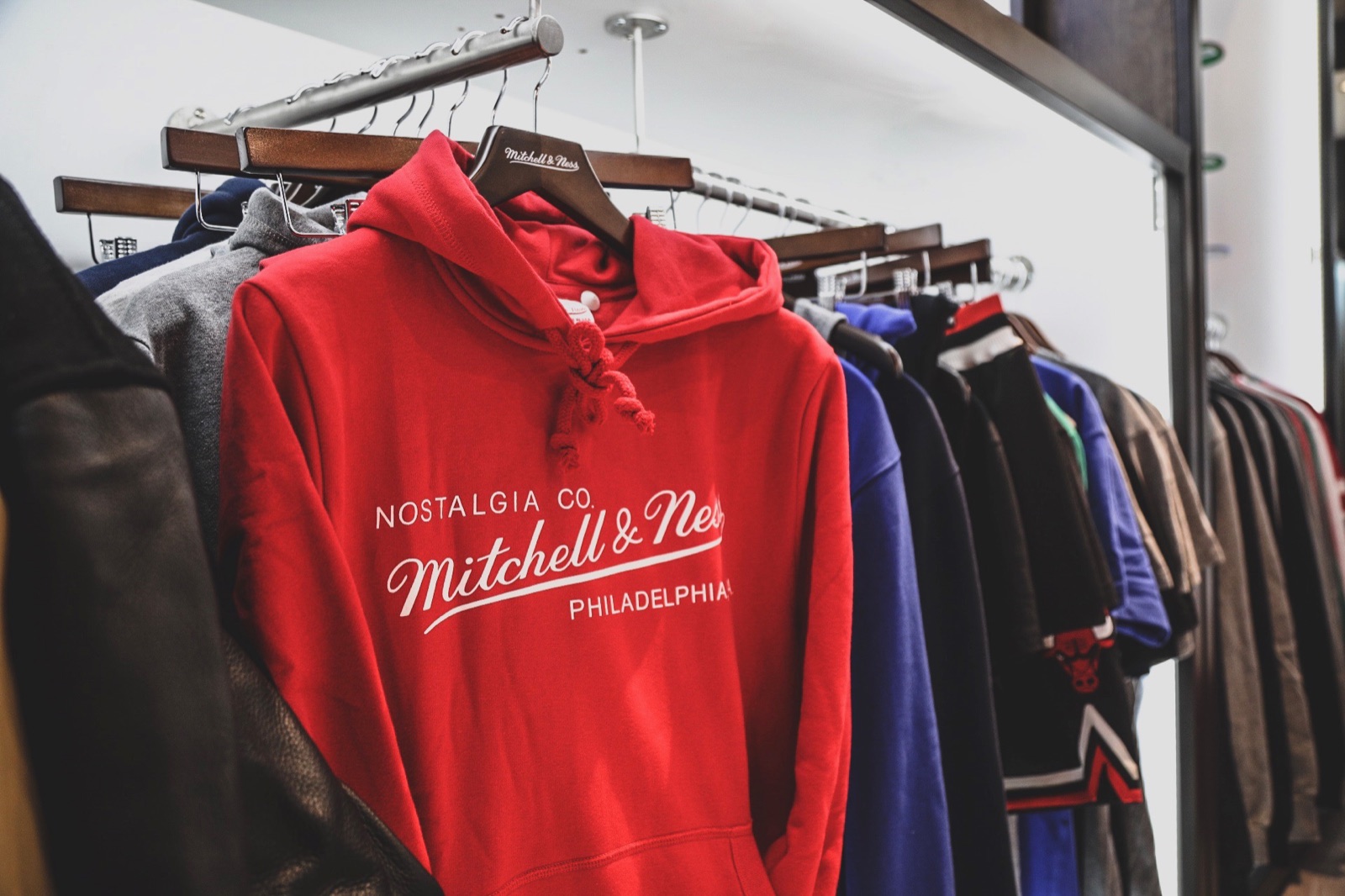 A rack of Mitchell & Ness apparel including a Philadelphia hoodie